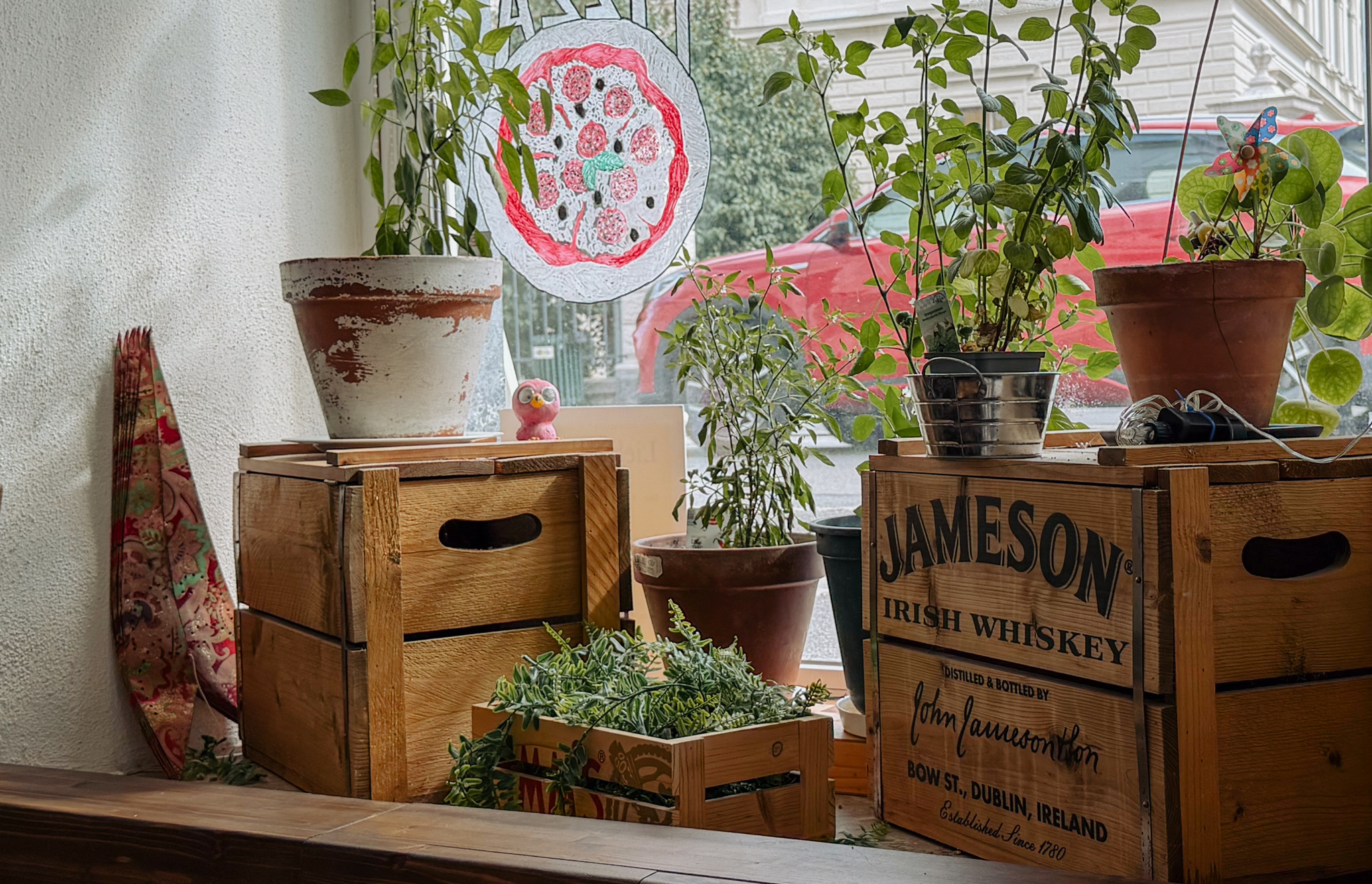Holzkisten mit Pflanzen und Deko am Fenster